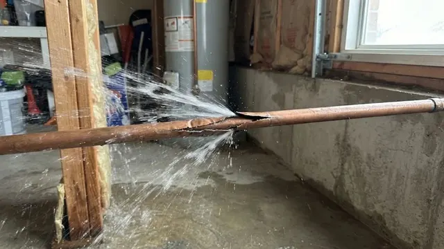 Split copper pipe spraying water in a basement, the damage a frozen pipe can cause