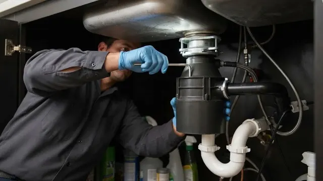 Plumber installing a garbage disposal under a kitchen sink